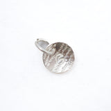 A small silver circular disc charm with a textured, hammered surface and a small attached metal loop, shown on a plain white background.
