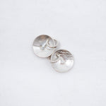 A pair of silver oval stud earrings with a hammered texture, displayed on a clean white background.