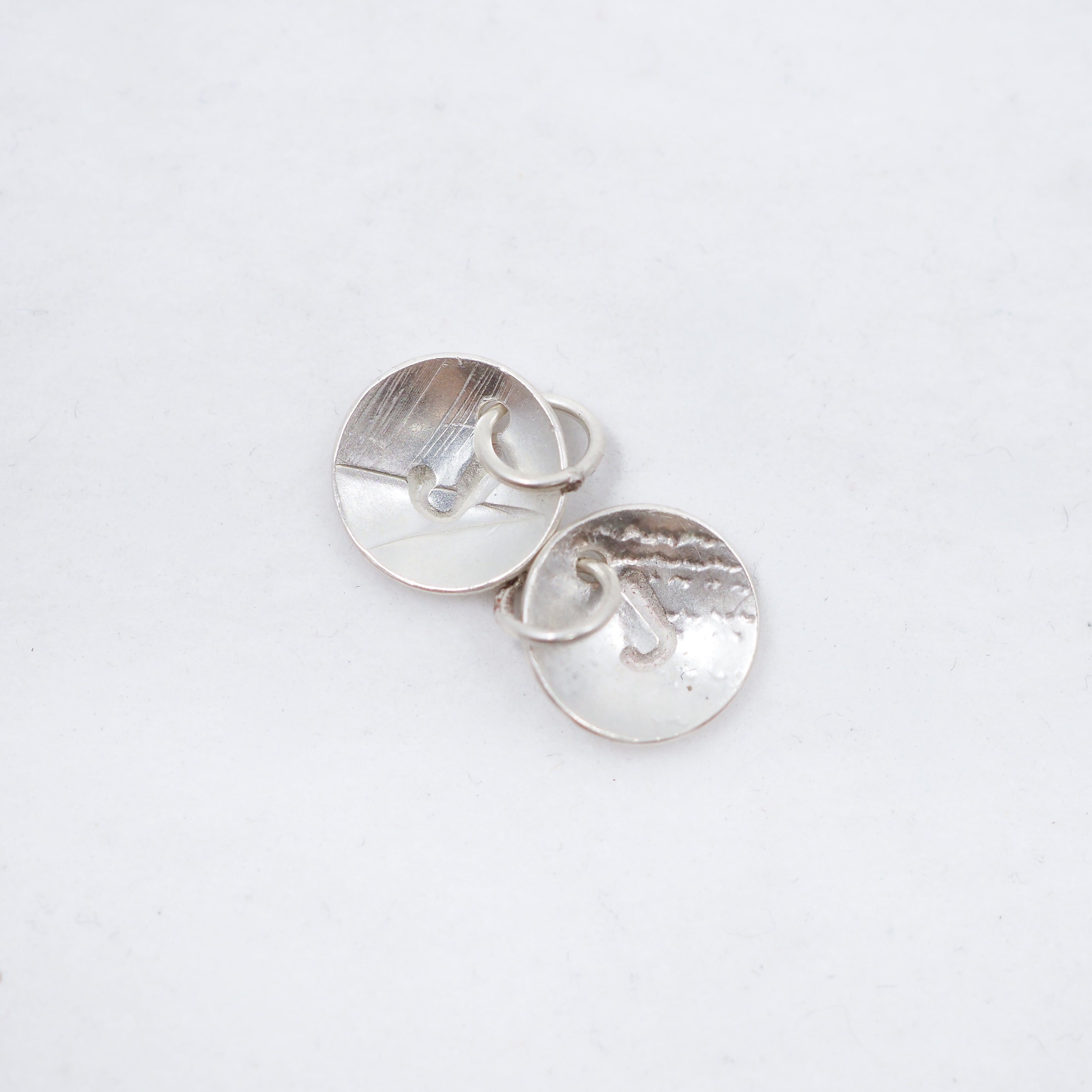 A pair of silver oval stud earrings with a hammered texture, displayed on a clean white background.