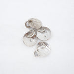 Four textured silver disc charms with small jump rings, arranged on a plain white background.