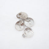 Four textured silver disc charms with small jump rings, arranged on a plain white background.