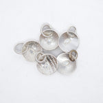 Five textured silver disc charms with attached jump rings, arranged on a plain white background.