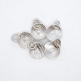 Five textured silver disc charms with attached jump rings, arranged on a plain white background.