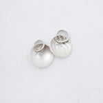 Two small silver discs both with attached jump rings, on a white background.