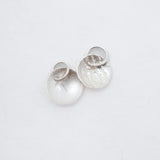 Two small silver discs both with attached jump rings, on a white background.