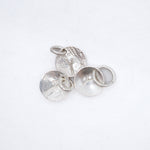 Four textured silver jewelry findings, including two round disc charms with loops and two flat round bases with ring settings, arranged on a clean white background.