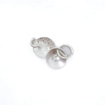 Three silver metal jewelry findings, including a textured disc, a flat disc, and a small ring, arranged on a plain white background.
