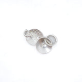 Three silver metal jewelry findings, including a textured disc, a flat disc, and a small ring, arranged on a plain white background.