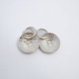 Five silver disc charms, each engraved with the letter A, arranged on a plain white background.