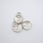 Three textured silver disc charms with attached jump rings, displayed on a clean white background.