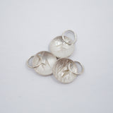 Three textured silver oval charms with lightning bolt details and attached split rings, arranged on a plain light gray background.