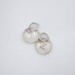 Two textured sterling silver disc charms with engraved letter Z and attached jump rings, displayed on a clean white background.