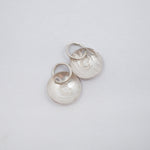 Two textured silver oval charms with a raised letter 'B' and jump rings, displayed on a clean white background.