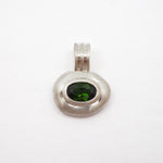 A silver pendant with a textured, organic oval shape featuring a dark green oval gemstone in the center, set against a plain white background.