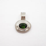 A silver pendant with a textured, organic oval shape featuring a dark green oval gemstone in the center, set against a plain white background.