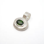A sterling silver pendant with a textured, organic-shaped bezel setting holding a dark green oval gemstone, shown on a plain white background.