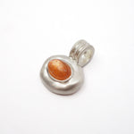 A sterling silver pendant featuring a textured, organic-shaped bezel set with a smooth, oval orange cabochon gemstone, shown on a plain white background.