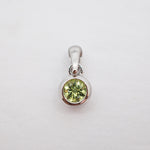 A sterling silver pendant featuring a round-cut light green gemstone in a bezel setting, shown on a plain white background.