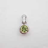 A sterling silver pendant featuring a round-cut light green gemstone in a bezel setting, shown on a plain white background.