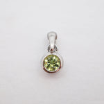A sterling silver pendant featuring a round-cut light green gemstone in a bezel setting, shown on a plain white background.