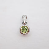 A sterling silver pendant featuring a round-cut light green gemstone in a bezel setting, shown on a plain white background.