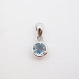 A sterling silver pendant featuring a round-cut light blue gemstone in a bezel setting, suspended from a polished bail against a plain white background.
