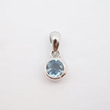 A sterling silver pendant featuring a round-cut light blue gemstone in a bezel setting, suspended from a polished bail against a plain white background.