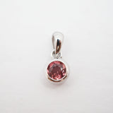 A silver pendant with a round pink gemstone in a bezel setting, shown on a plain white background.