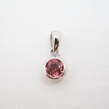 A silver pendant with a round pink gemstone in a bezel setting, shown on a plain white background.