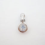 A sterling silver pendant charm featuring a bezel-set round iridescent moonstone gemstone, shown on a plain white background.