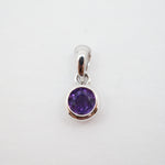 A sterling silver pendant charm featuring a round-cut purple gemstone in a bezel setting, shown on a plain white background.