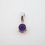 A sterling silver pendant charm featuring a round-cut purple gemstone in a bezel setting, shown on a plain white background.
