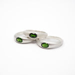 Three silver rings with oval green gemstones, arranged on a plain white background.