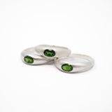 Three silver rings with oval green gemstones, arranged on a plain white background.