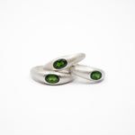 three silver curved rings with oval green gemstones, photographed on a clean white background.