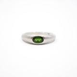 A silver band ring featuring a round green gemstone in a bezel setting, photographed against a seamless white background.