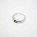 A silver-toned ring with a small oval green gemstone, photographed on a plain white background.