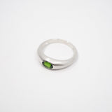 A silver-toned ring with a small oval green gemstone, photographed on a plain white background.