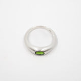 A silver band ring featuring a small oval green gemstone set in the center, photographed on a plain white background.