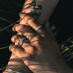 Two hands holding each other with a leafy background