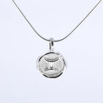 A silver necklace featuring a round pendant with a zodiac sign on it, attached to a delicate chain.