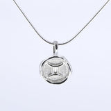 A silver necklace featuring a round pendant with a zodiac sign on it, attached to a delicate chain.