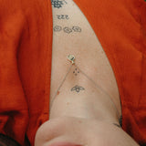 Person wearing an orange garment with visible tattoos on their neck and shoulders, wearing the wave love pendant. 